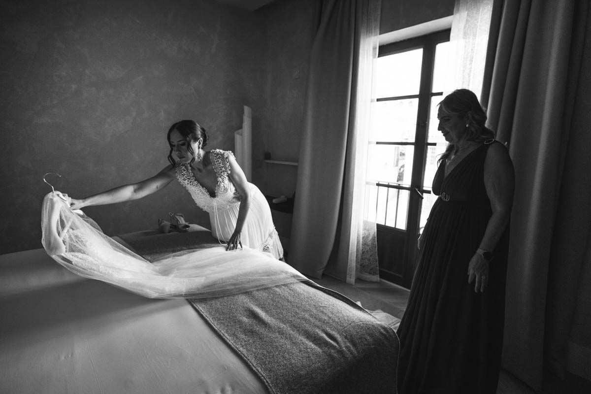 Fotógrafo en Córdoba novia con su madre en los preparativos antes de su boda tratando con mimo su traje